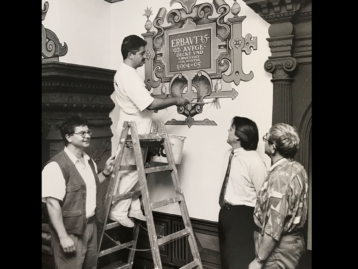 Malermeister bei Restaurierungsarbeiten in historischem Gebäude in Heidelberg. Teamarbeit und Handwerkskunst.