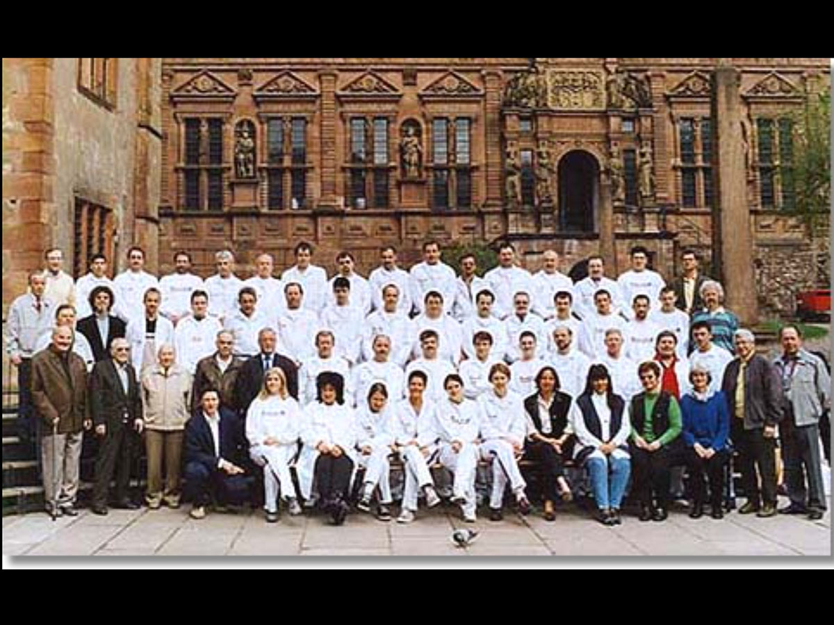 Gruppenfoto von Maler Eck Team vor historischem Gebäude in Heidelberg, Malermeister und Mitarbeiter in Arbeitskleidung.