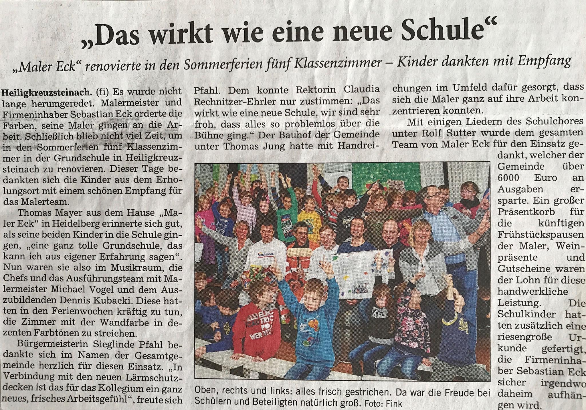 Kinder und Malerteam feiern renovierte Klassenzimmer in Heidelberg.